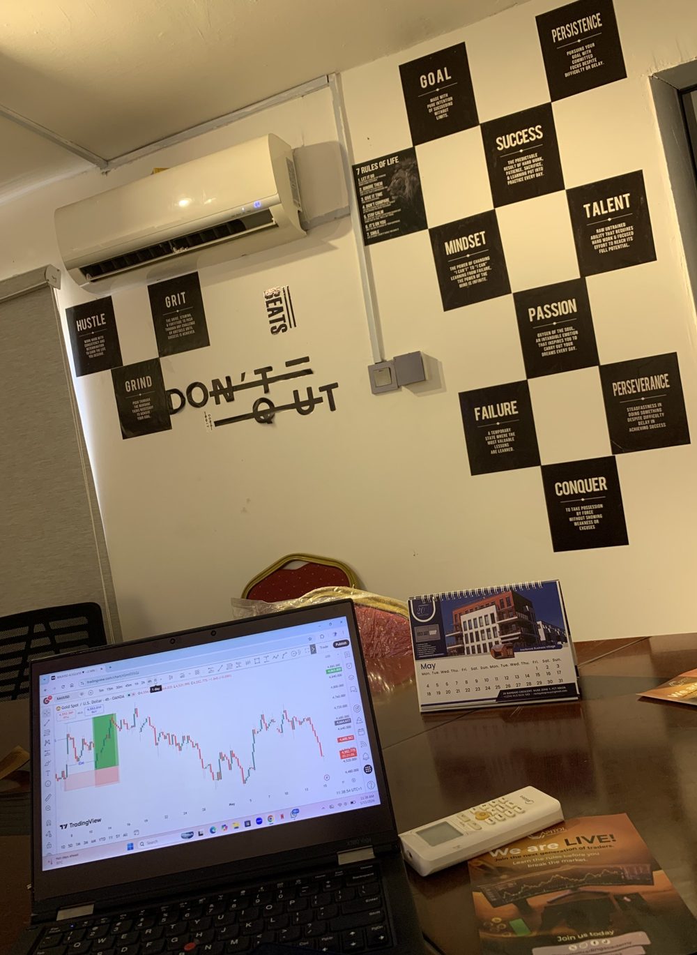 The Next Point trading room in Abuja, with a live gold chart on a laptop and motivational posters on the wall
